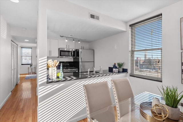 kitchen featuring white cabinetry, sink, stainless steel appliances, and light wood-type flooring