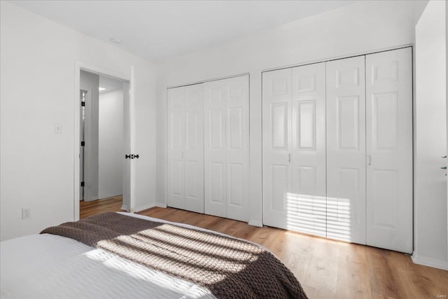 bedroom with two closets and light hardwood / wood-style flooring