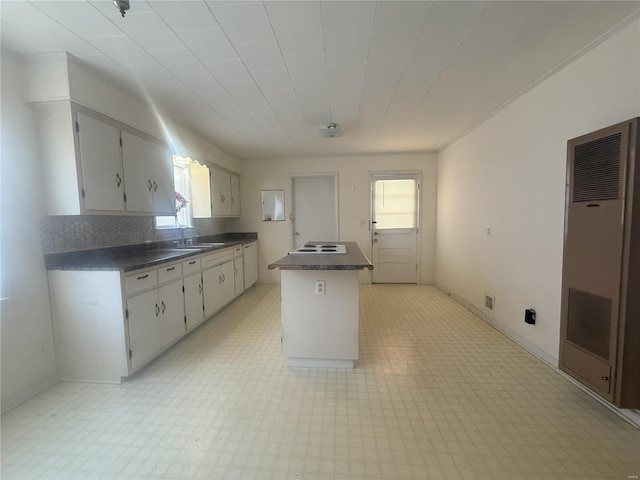 kitchen featuring sink, white cabinets, tasteful backsplash, electric cooktop, and a kitchen island