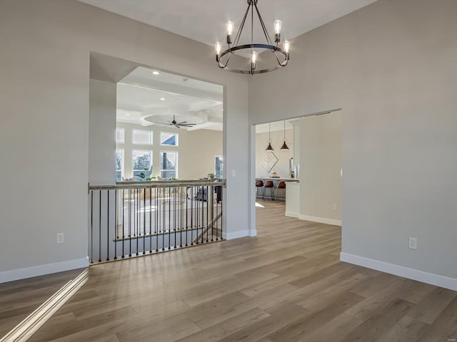 dining space featuring a high ceiling, wood-type flooring, and ceiling fan with notable chandelier