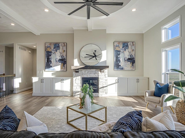 living room featuring beamed ceiling, ceiling fan, a fireplace, and light hardwood / wood-style floors