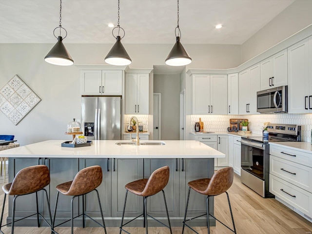 kitchen with stainless steel appliances, white cabinets, and a center island with sink