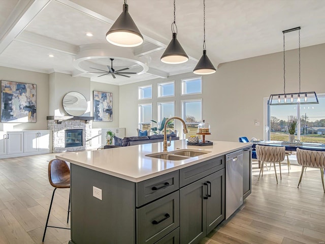 kitchen with pendant lighting, sink, ceiling fan, a kitchen island with sink, and stainless steel dishwasher