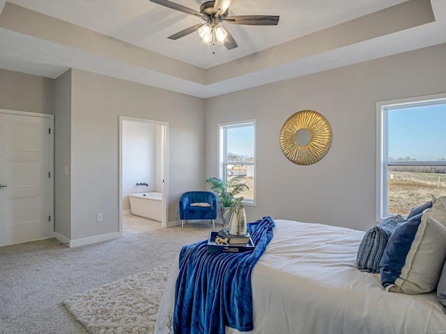 bedroom featuring ensuite bathroom, light carpet, ceiling fan, and a tray ceiling