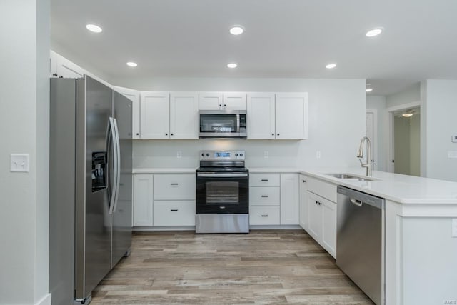 kitchen featuring sink, white cabinets, kitchen peninsula, and appliances with stainless steel finishes