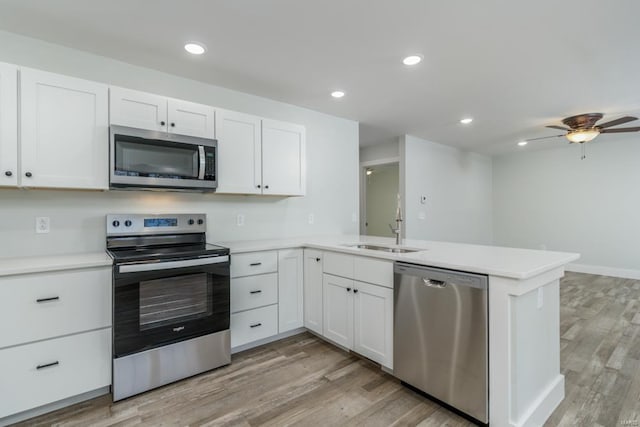 kitchen featuring sink, white cabinetry, kitchen peninsula, and appliances with stainless steel finishes