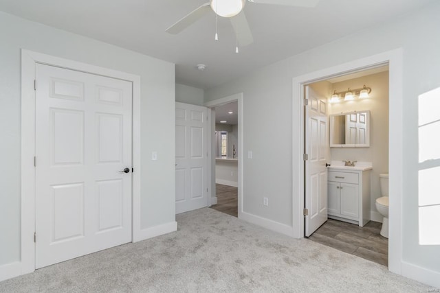 unfurnished bedroom with light colored carpet, ensuite bath, and ceiling fan