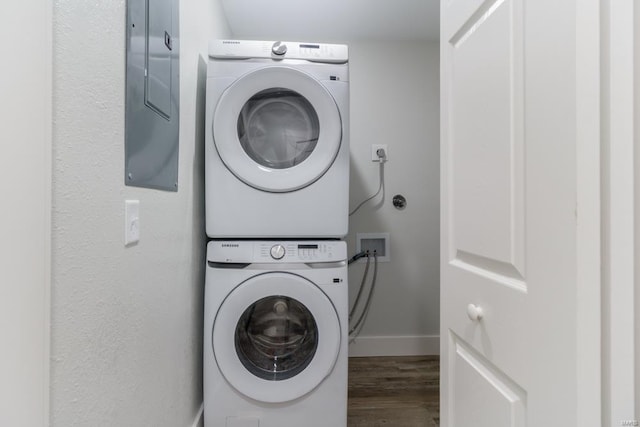 laundry area featuring stacked washer / dryer and dark hardwood / wood-style flooring