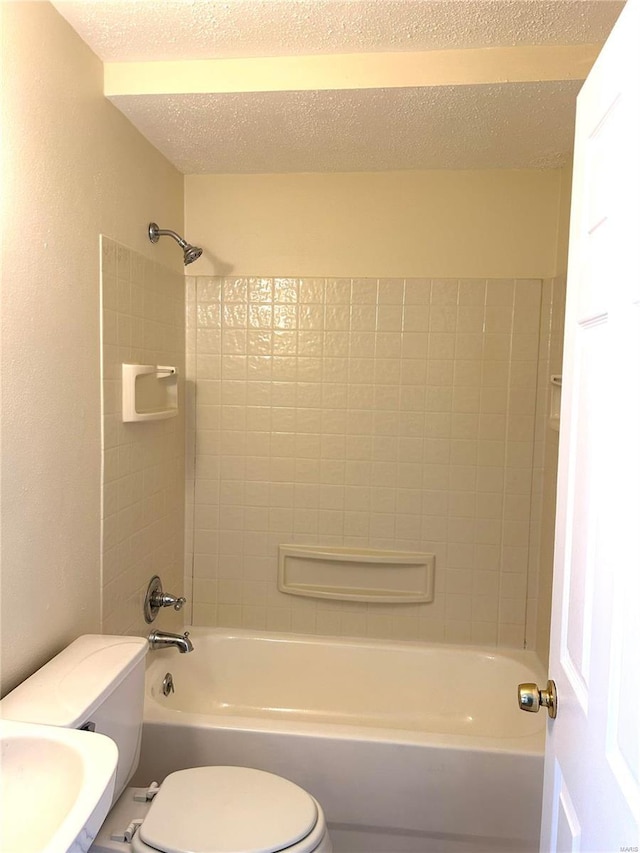 bathroom with toilet, tiled shower / bath combo, and a textured ceiling