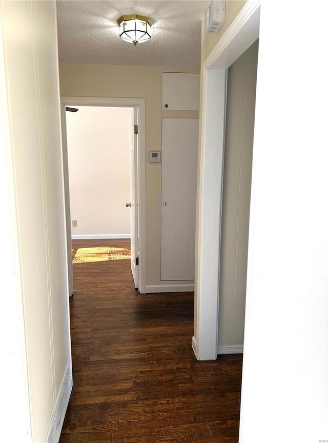 hall with dark wood-type flooring and a textured ceiling