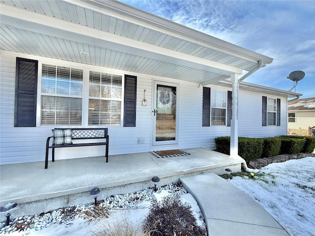 snow covered property entrance with covered porch