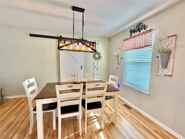 dining space with hardwood / wood-style floors and a barn door