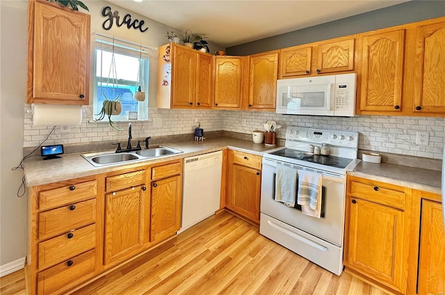 kitchen featuring sink, light wood-type flooring, white appliances, and tasteful backsplash