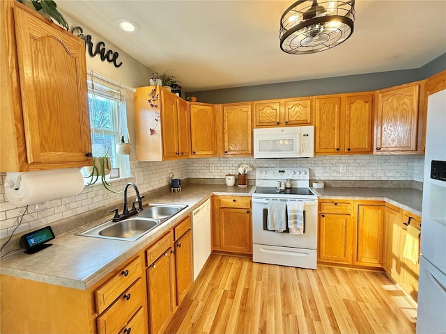 kitchen featuring sink, white appliances, light hardwood / wood-style floors, and tasteful backsplash