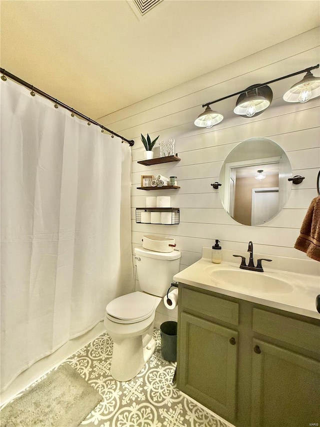 bathroom with toilet, wooden walls, tile patterned flooring, and vanity