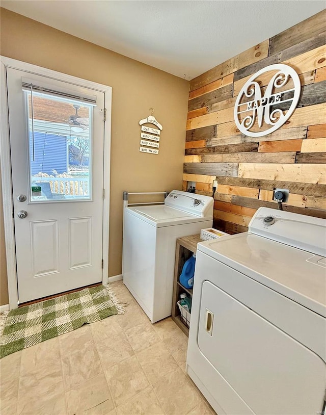 clothes washing area featuring washer and clothes dryer and wooden walls