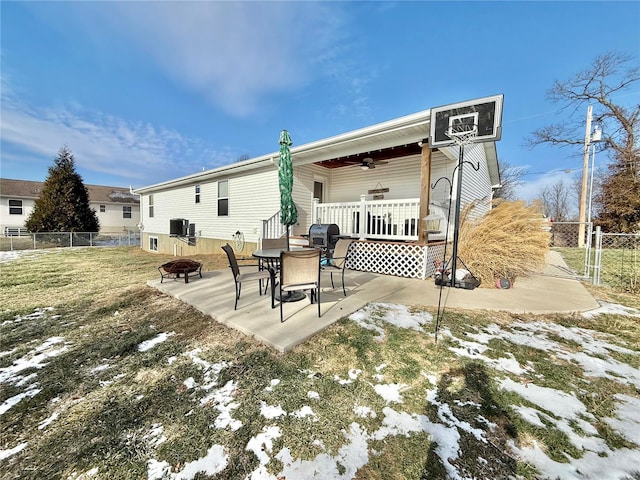 snow covered rear of property with a patio, central AC unit, a yard, and a fire pit