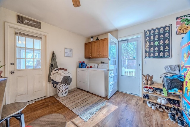 laundry room featuring cabinets, a wealth of natural light, separate washer and dryer, and light hardwood / wood-style flooring