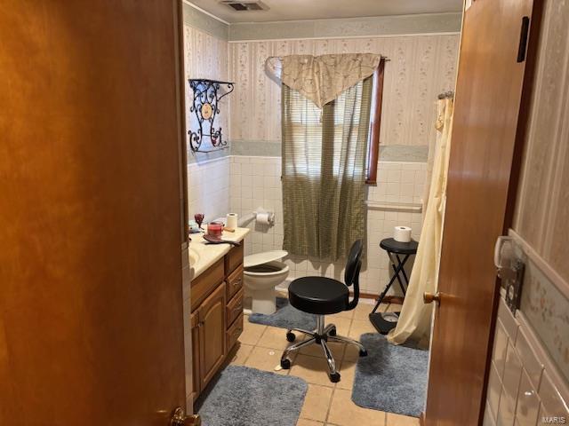 bathroom with vanity, toilet, tile walls, and tile patterned flooring