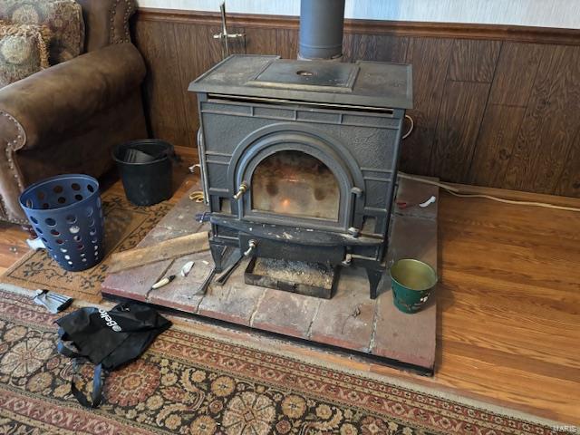 details with wood-type flooring, wooden walls, and a wood stove