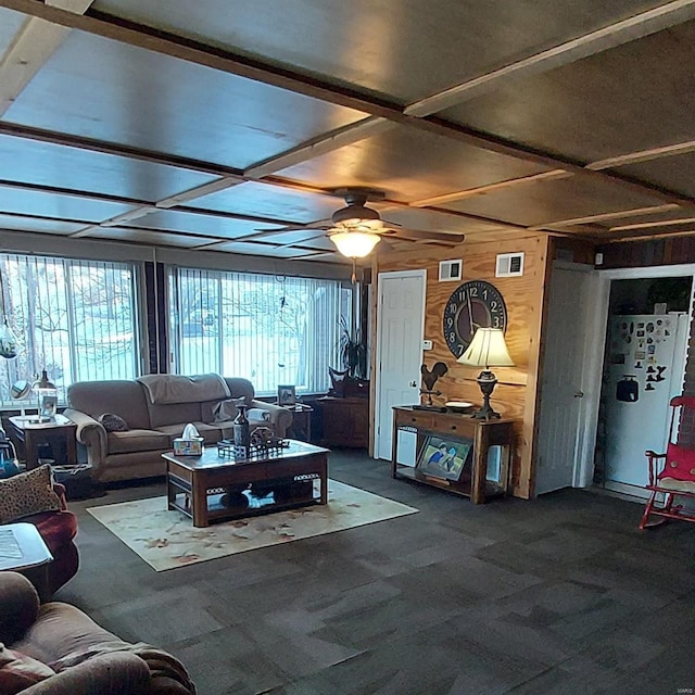 carpeted living room featuring ceiling fan and wood walls