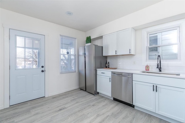 kitchen featuring sink, light wood-type flooring, white cabinetry, and stainless steel appliances