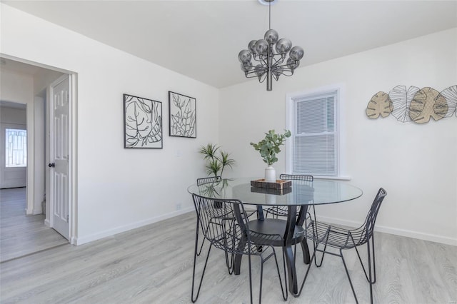 dining room with light hardwood / wood-style floors and a notable chandelier