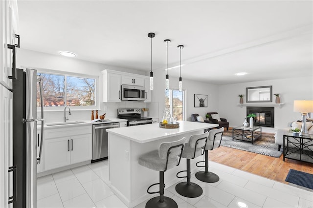 kitchen featuring white cabinets, stainless steel appliances, a kitchen island, and sink