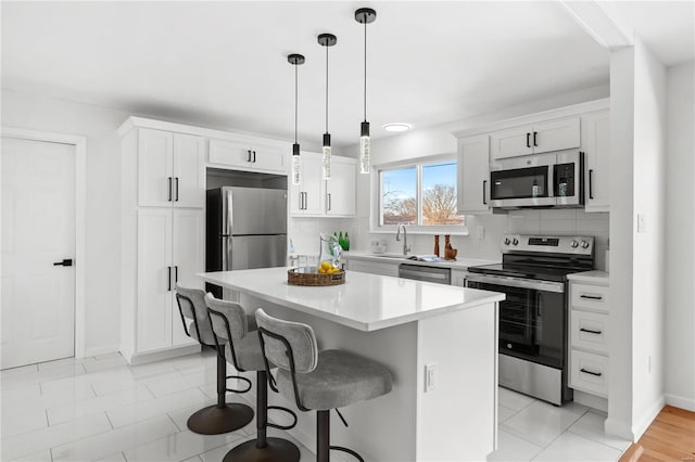 kitchen with decorative light fixtures, white cabinetry, a kitchen island, decorative backsplash, and stainless steel appliances