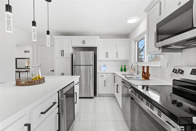 kitchen with white cabinetry, sink, pendant lighting, stainless steel appliances, and beverage cooler