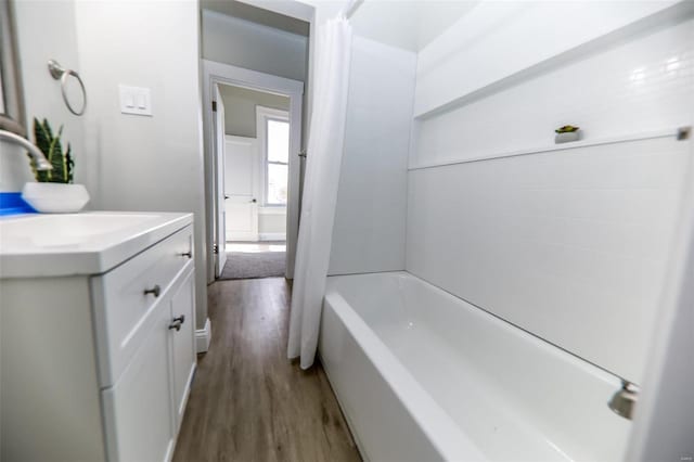 bathroom featuring hardwood / wood-style floors, shower / bathtub combination with curtain, and vanity