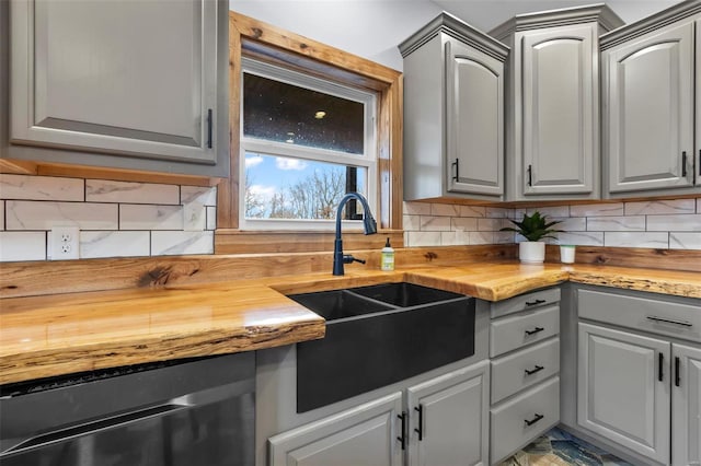 kitchen with sink, gray cabinets, dishwasher, backsplash, and wood counters