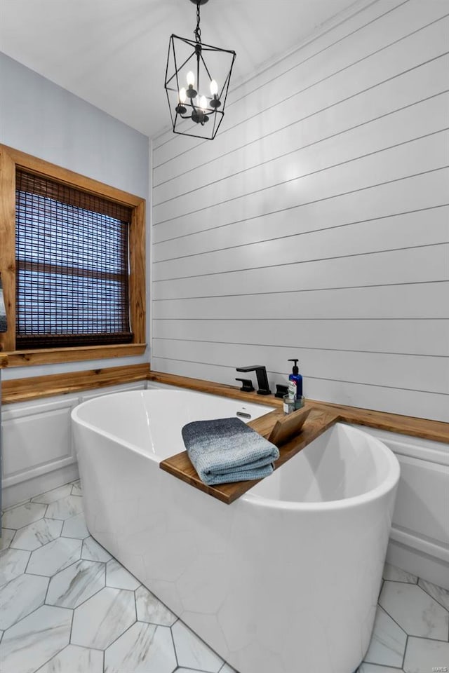 bathroom featuring a tub to relax in and a chandelier