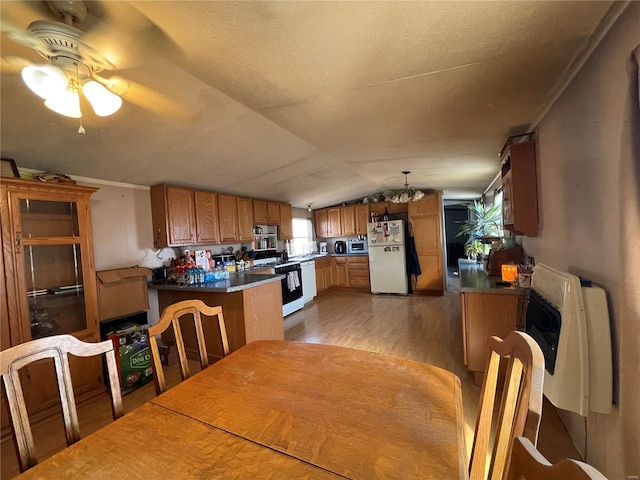 kitchen with kitchen peninsula, hanging light fixtures, white appliances, light hardwood / wood-style floors, and lofted ceiling