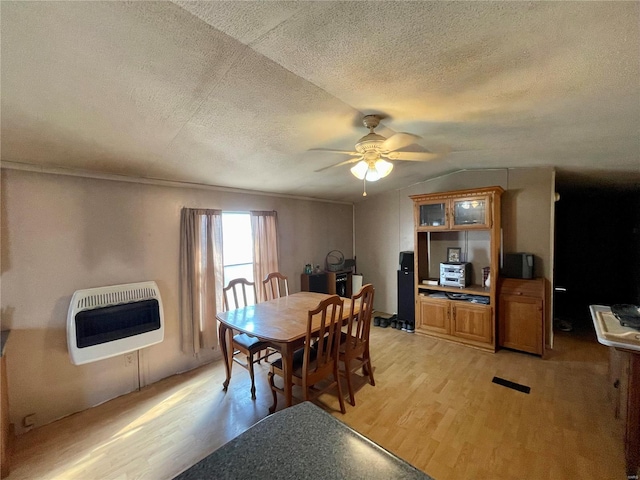 dining space featuring ceiling fan, light wood-type flooring, heating unit, and vaulted ceiling