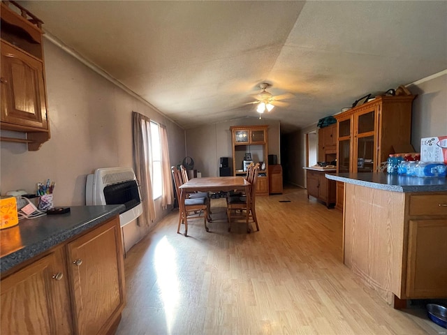 dining room featuring light hardwood / wood-style flooring, heating unit, vaulted ceiling, and ceiling fan