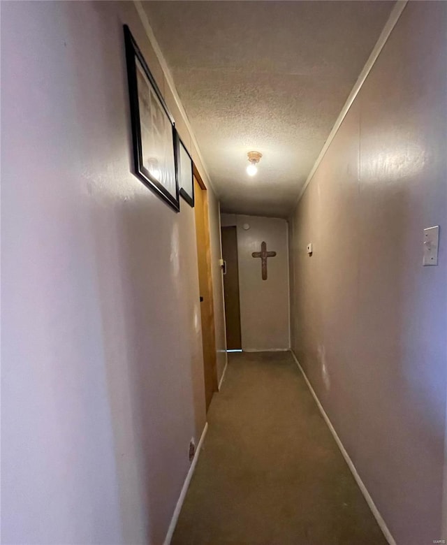 corridor with a textured ceiling, carpet flooring, and baseboards