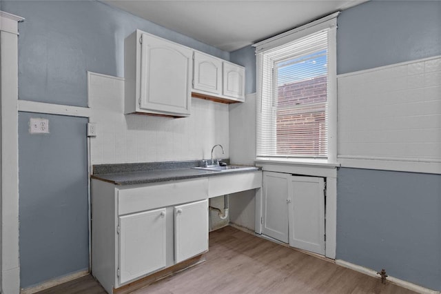 kitchen featuring white cabinetry, sink, and light wood-type flooring