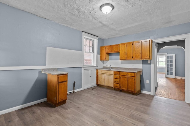 kitchen with sink, light hardwood / wood-style flooring, and a textured ceiling