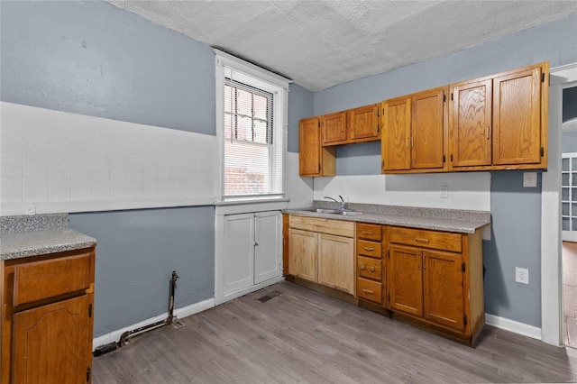 kitchen featuring sink, a textured ceiling, and light hardwood / wood-style floors