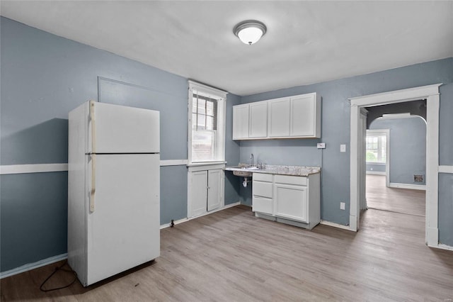 kitchen featuring white fridge, sink, white cabinets, and light hardwood / wood-style floors