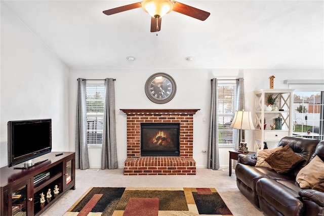 carpeted living room with ceiling fan and a fireplace