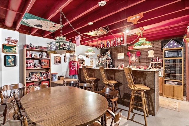 interior space featuring a community bar, brick wall, and concrete flooring