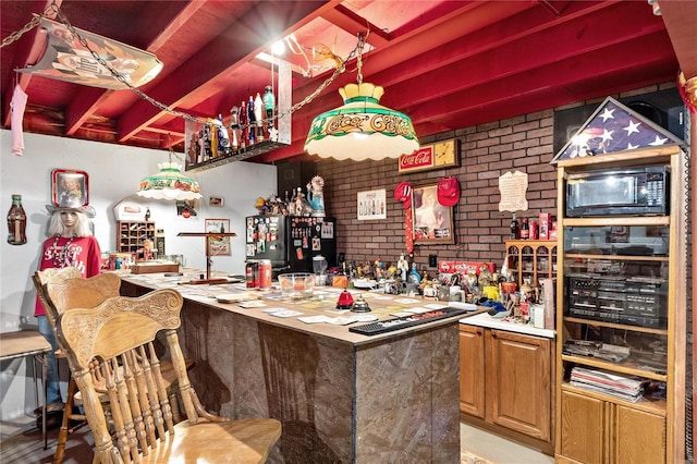 bar with indoor wet bar, beam ceiling, brick wall, and black microwave