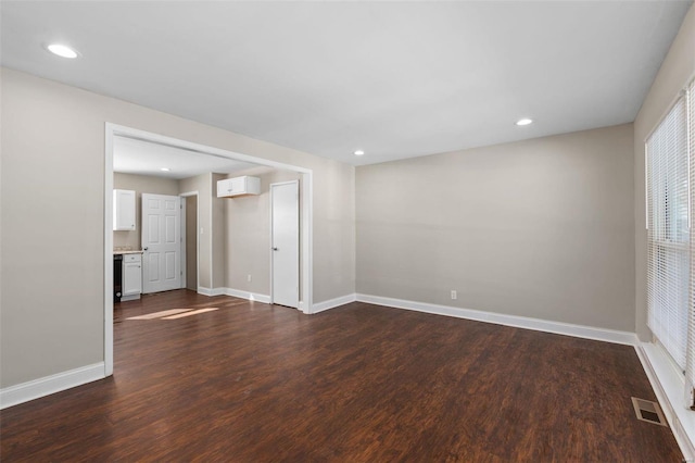 spare room with a wall unit AC and dark hardwood / wood-style flooring