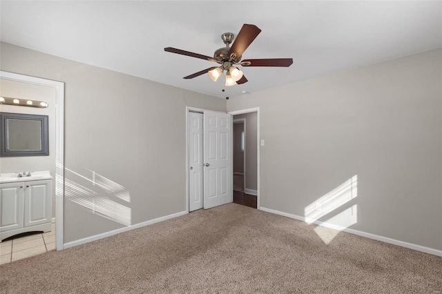 unfurnished bedroom with sink, ceiling fan, connected bathroom, and light carpet