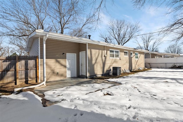 snow covered rear of property with central air condition unit