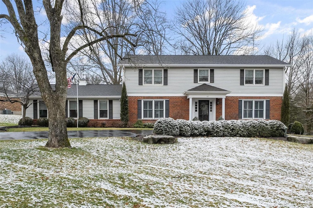 view of front of home with brick siding and a chimney