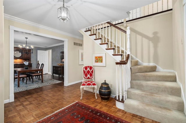 stairway featuring crown molding, an inviting chandelier, visible vents, and baseboards