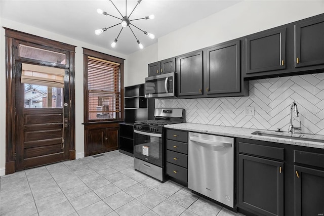 kitchen with sink, light tile patterned floors, stainless steel appliances, light stone countertops, and decorative backsplash